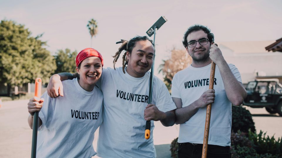 Three people standing and smiling with volunteer t shirts